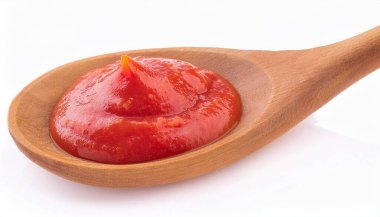 Tahta kaşık dolusu domates sosu ve beyaz arka planda taze fesleğen..
