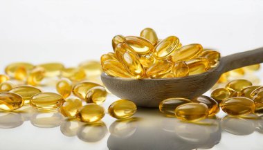 Golden yellow pills in a spoon and scattered on the floor. Softgel of food supplements, fish oil, omega 3, vitamin D3, vitamin E oil filled capsules. clipart