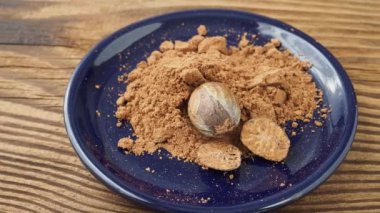 Nutmeg whole and grated in ceramic bowl