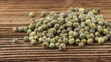 Dried green peppercorn. Dry green pepper spice on wooden table.
