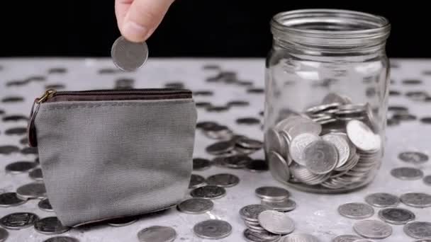 女性は小さな変更グレーの財布に5セントを入れて 散乱銀ウクライナのコイン ペニー ガラスの貯金箱は テーブルのぼやけた背景にあります — ストック動画