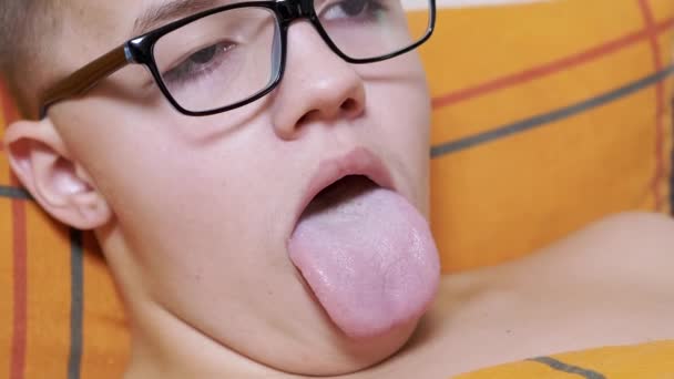 Adolescente Con Gafas Acostado Una Cama Abriendo Boca Mostrando Lengua — Vídeos de Stock