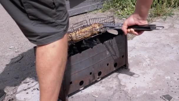 男性はグリルでジューシーな肉を調理します 日光の光線で裏庭にバーベキュー 火の上でケバブを調理 静止グリルで 煙と熱い石炭のストーブ 体の部分 — ストック動画