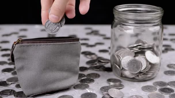 小さな変更グレーの財布にいくつかのセントを入れて女性 散乱銀ウクライナのコイン ペニー ガラスの貯金箱は テーブルのぼやけた背景にあります — ストック動画
