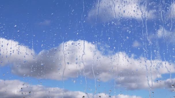 Σταγόνες Βροχής Ρέουν Κάτω Από Γυαλί Ένα Φόντο Κινούμενων Νεφών — Αρχείο Βίντεο
