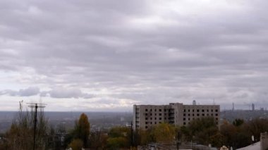 Terk Edilmiş Binanın Arkaplanına Karşı Gri Kümülüs Bulutları Taşımak. Şehrin kasvetli panoramik manzarası, fabrika ve rüzgarda sallanan ağaçlar. Sonbahar havası bulutlu. Ufuk. Doğa, kuşlar.