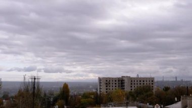 Terk Edilmiş Binanın Arkaplanına Karşı Gri Kümülüs Bulutları Taşımak. Şehrin kasvetli panoramik manzarası, fabrika ve rüzgarda sallanan ağaçlar. Sonbahar havası bulutlu. Ufuk. Doğa, kuşlar.