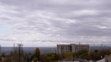 Terk Edilmiş Binanın Arkaplanına Karşı Gri Kümülüs Bulutları Taşımak. Şehrin kasvetli panoramik manzarası, fabrika ve rüzgarda sallanan ağaçlar. Sonbahar havası bulutlu. Ufuk. Doğa, kuşlar.