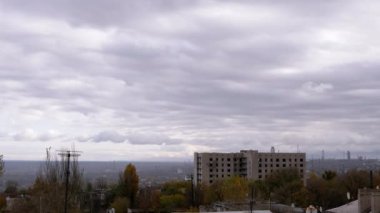 Terk Edilmiş Binanın Arkaplanına Karşı Gri Kümülüs Bulutları Taşımak. Şehrin kasvetli panoramik manzarası, fabrika ve rüzgarda sallanan ağaçlar. Sonbahar havası bulutlu. Ufuk. Doğa, kuşlar.