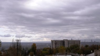 Terk Edilmiş Binanın Arkaplanına Karşı Gri Kümülüs Bulutları Taşımak. Şehrin kasvetli panoramik manzarası, fabrika ve rüzgarda sallanan ağaçlar. Sonbahar havası bulutlu. Ufuk. Doğa, kuşlar.
