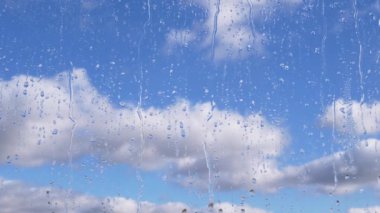 Yağmur Damlaları, Hareket Eden Bulutlar ve Mavi Gök 'ün Arkaplanına Karşı Camdan Aşağı Akıyor. Zaman atlaması. Yavaş hareket eden kümülüs bulutları. Yağmurlu bir hava. Camdan aşağı akan su akıntıları. Meteoroloji.