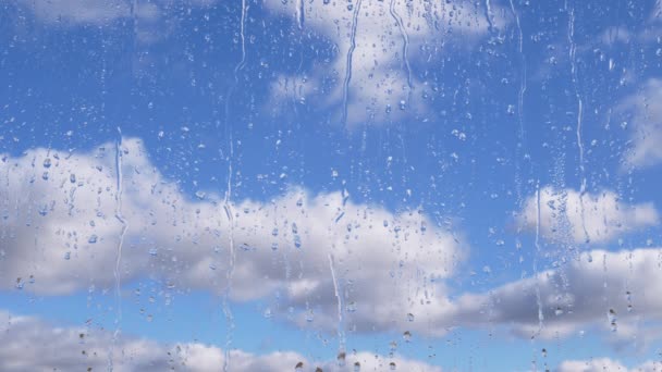 雨滴在流动的云彩和蓝天的背景下顺着玻璃流下 时间流逝 缓慢移动的积雨云 一股水流从玻璃窗流下来 气象学 — 图库视频影像