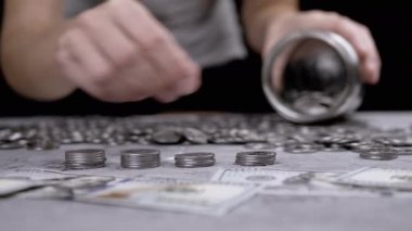 Glass Jar ya da Piggy Bank 'a Gümüş Para Yığını Koyan Kadın. Bir sürü sent, nakit para beton bir zeminde yatıyor. Bütçe, harcama, tasarruf, birikim. Zenginlik, yoksulluk. Mali işler. Stok.