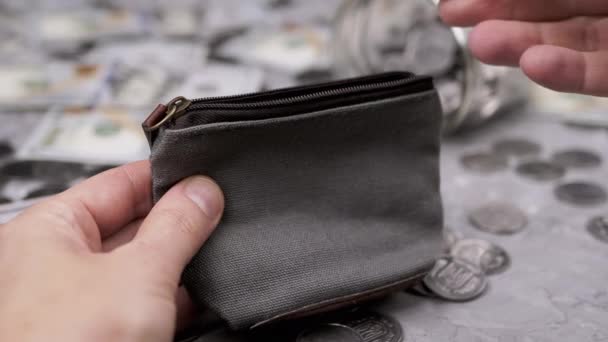 女人把一些硬币放进一个小纺织品变灰的皮包里 散落的100美元钞票 美分和玻璃储蓄罐放在桌子模糊的背景上 — 图库视频影像
