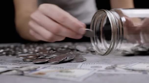 Frau Füllt Ein Glasgefäß Mit Silbermünzen Die Auf Einem Tisch — Stockvideo