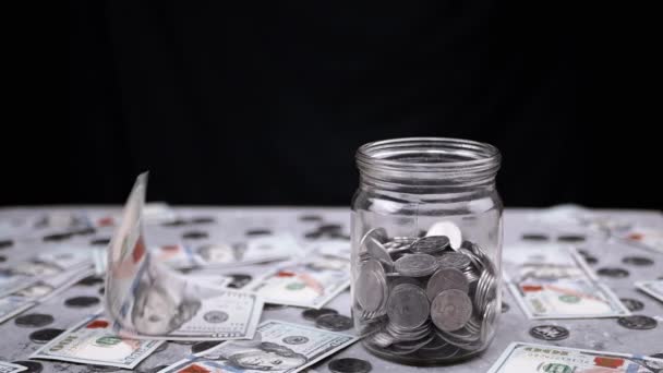 ドル紙幣は 変化のあるガラス瓶と散乱お金のあるテーブルに落ちます ウクライナの銀5コペック硬貨の散乱 貯金箱だ お金の蓄積 — ストック動画