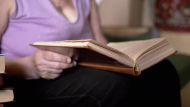 高齢の女性は本を読んで 日光室内の光線でページをめくる 接近中だ 年金受給者は手に本を持ち 勉強し 家で退職する 高齢者の生活様式 — ストック動画