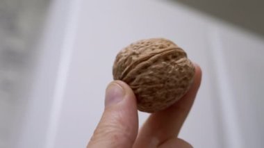 Çiftçi El Tutuşu ve Bulanık Arka plan 'da Büyük Ceviz Gösterimi. Yakın plan. Sonbahar hasadı. Faydalı, diyet sağlıklı yemek. Beyin gıdası. Vejetaryenlik. Olgun kahverengi ceviz kabuğu. Doku. Yavaş çekim.