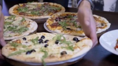 Garson, Masa 4 'e Büyük Lezzetli Pizzalar sipariş etti. Masa ayarı. Müşteri hizmetleri. Bir grup insan için farklı malzemeli pizza. Zeytin, roka, parmesan, jambon..