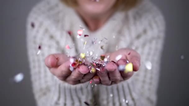 Szczęśliwa Kobieta Dmucha Błyszczące Kolorowe Konfetti Dłoniach Niewyraźne Tło Zbliżenie — Wideo stockowe