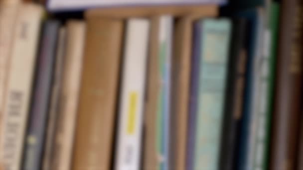 模糊的背景 旧书在家里的书架上排成一排 家庭图书馆书架上的书 摄像机从右到左的运动 知识的概念 — 图库视频影像