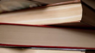 Güneş Işıkları 'ndaki Renkli Eski Hardcover Kitapları' nın yakın çekimi. Kamera baştan aşağı hareket ediyor. Ev kitapları koleksiyonu. Gün ışığı. Öğrenme, okuma ve bilgi kavramı.