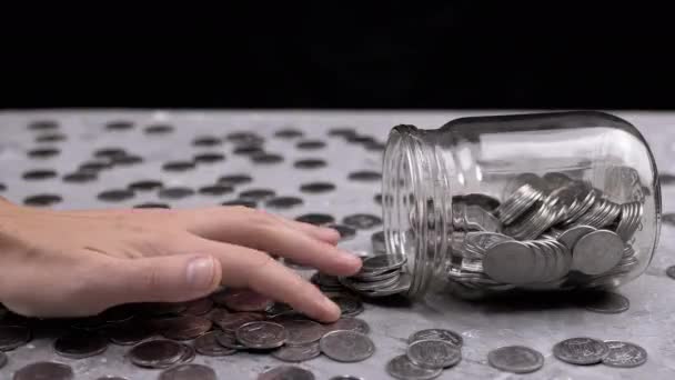 女性の手反転ガラスジャーからテーブルの散乱コインをカウントします 灰色のコンクリートの背景にペニーの多く 金融危機 お金の蓄積 現金だ — ストック動画