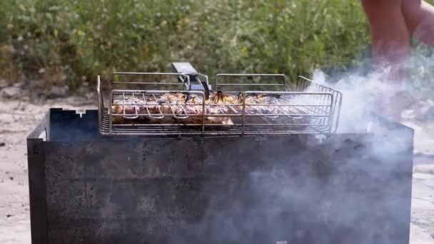 男性はグリルでジューシーな肉を調理します 日光の光線で裏庭にバーベキュー 火の上でケバブを調理 静止グリルで 煙と熱い石炭のストーブ 体の部分 — ストック動画
