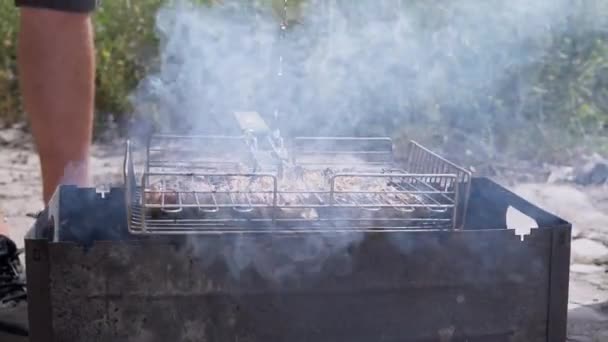 在烧烤烤架上 有人把一条细细的水流扔进燃烧的火中 烹调多汁的牛排 烤肉在外面的煤块 扑灭了一场大火 靠近点 — 图库视频影像