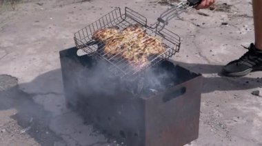 Erkek, Izgarada Sulu Et Pişirir, Güneş Işığında Bir Arka Bahçede Barbekü. Açık ateşte kebap pişiriyorum, ızgarada, kızgın kömürde duman, kül. Ayaklar. Vücut parçası. Hafta Sonu.