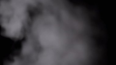 Icy White Foggy Cloud of Flying Steam on a Black Background. Abstract background. Bokeh effect. Thick fog and smoke fill the empty space. Blurred focus. Ice cloud steam. Floating mist. Slow-motion.