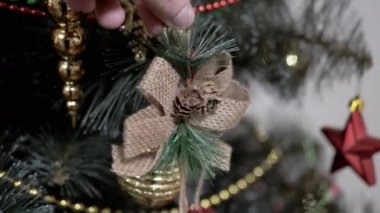 Yaklaş Eller, Noel Ağacı 'nı Parlak Altın Toplarla süsle. Ağacın dalındaki oyuncak. İnsan eli. Noel süsü, dekorasyon, ev dekorasyonu. Tatil günü. Olumlu duygular. Mutlu aile kavramı. 4K.