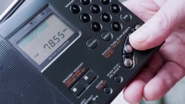 Kara Tozlu Modern Taşınabilir Radyo Alıcısı 'nda Frekans Aranıyor. Erkek parmakları düğmeye basarak FM dalgalarını arayın. İkili dönüşüm, elle akort, tarama istasyonu. Dijital ekran, kanal değişimi.