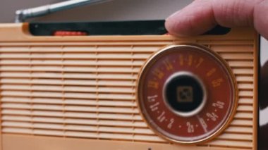 Yakın plan, Erkek Parmaklar Eski Vintage Retro alıcıda Frekansı Ayarlar. Bant ayarı, FM dalgalarının frekans araması, dönüş kadranı. Manuel ayarlı eski sarı taşınabilir radyo alıcısı. 60 'lar, 70' ler.