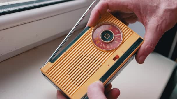 近距离 男性手指在一个老式复古接收机上调整频率 波段设置 调频波频搜索 旋转拨号 旧的黄色手提式无线电接收机 带有手动调音 70年代 — 图库视频影像