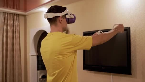 Мужчина Очках Игровыми Контроллерами Играющий Видеоигре Комната Парень Белом Шлеме — стоковое видео