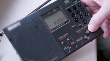 Kara Tozlu Modern Taşınabilir Radyo Alıcısı 'nda Frekans Bulmak. Erkek parmakları düğmeye basarak FM dalgalarını arayın. İkili dönüşüm, elle akort, tarama istasyonu. Dijital ekran, kanal değişimi.
