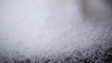 Granulated Sugar 'ın Beyaz Kristalleri Yavaş Çekimde Siyah Arkaplan' a Düşüyor. Yakın plan. Şeker parçacıkları akışı yüzeyi doldurur. Granüller. Doku, soyut arkaplan. Şeker tüketimi.