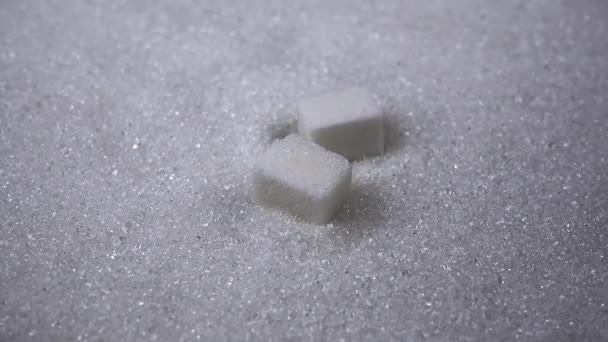 精製されたシュガーキューブは白シュガーの表面に落ちます 閉めろ スローモーション 砂糖のハード部分は グラニュー糖の山の中で崩れます 顆粒だ テクスチャ 抽象的な背景 記事だ 糖尿病 — ストック動画