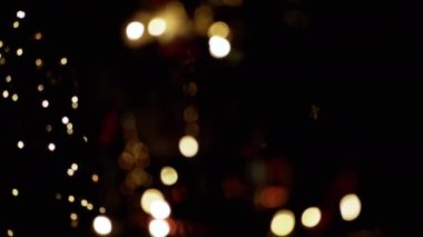 Yanıp sönen Noel Ampulleri, bulanık bir Noel Ağacı Arkaplanındaki Oyuncaklar. Göz kırpan altın ampuller ve çelenklerle odaklanmamış soyut bir arka plan. Bulanık bokeh. Noel süsü. Xmas.