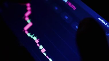 Gece Karanlık Oda 'da Cep Telefonu Uygulamasında Kripto Para Tablosu. Tüccar akıllı telefon ekranına parmağıyla dokunuyor. Dinamik, istatistik, büyüme, düşüş. Borsa. Gelecek fiyatı. Bitcoin.