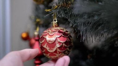 Yaklaş, Eller Ağaç Dalında Noel Balosu. Parlak kırmızı, altın mücevher. Noel süsü, dekorasyon, ev dekorasyonu. Tatil günü. Olumlu duygular. Mutlu aile kavramı. Yavaş çekim.