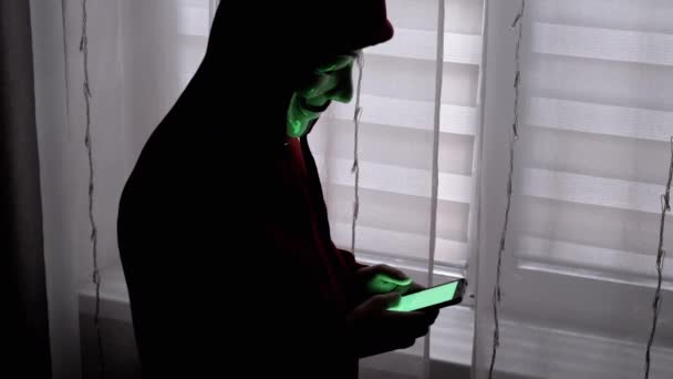 Hacker Mask Sosteniendo Teléfono Inteligente Las Manos Con Una Pantalla — Vídeo de stock