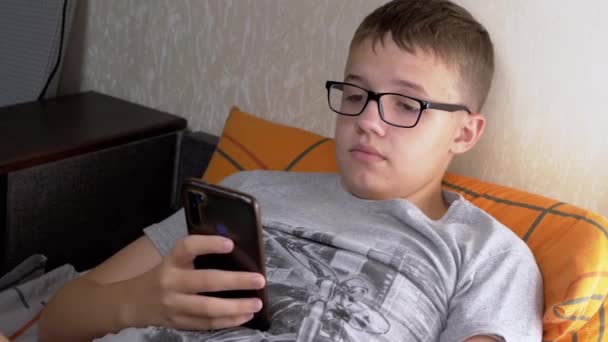 Dziecko Okularach Leżące Kanapie Grające Gry Wideo Smartfonie Pokoju Zmęczony — Wideo stockowe