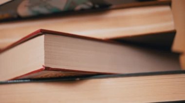 Güneş Işıkları 'ndaki Renkli Eski Hardcover Kitapları' nın yakın çekimi. Kamera baştan aşağı hareket ediyor. Ev kitapları koleksiyonu. Gün ışığı. Öğrenme, okuma ve bilgi kavramı.