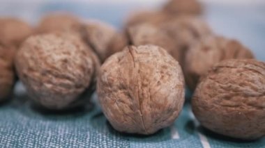 Masanın üzerinde bir yığın hasat edilmiş, olgun kahverengi ceviz var. Yakın plan. Sonbahar hasadı. Faydalı, diyet sağlıklı yemek. Beyin gıdası. Vejetaryenlik. Vitaminler. Ceviz kabuğu. Doku. Yavaş çekim. Büyüt.