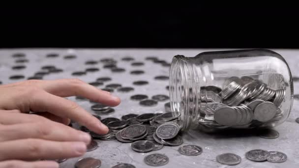 用倒立玻璃瓶数着桌上散落的硬币的女性手 灰色混凝土背景上有很多便士 金融危机 资本积累 — 图库视频影像