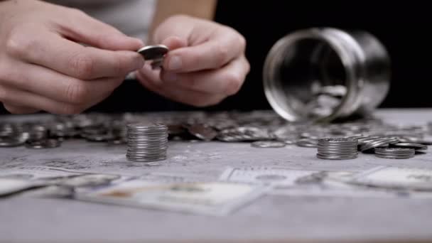 女性的手从散落的钱附近的一堆堆硬币中建造一座塔 玻璃瓶 猪银行 手把分币放在塔顶上 金融危机 — 图库视频影像