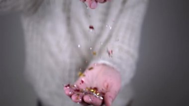 Eller Tinsel 'in Parlak Işıltılarıyla, Konfeti Bulanık Arkaplanda Oynuyor. Yakın plan. Parlak renkli bir konfeti kıvrılıyor ve bir hava girdabına düşüyor. Noel, yeni yıl, parti. Mutlu insanlar..