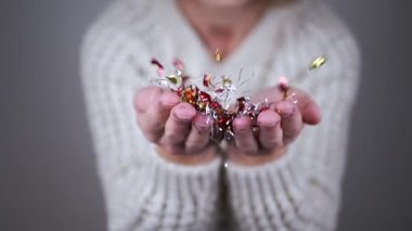 Bulanık Arkaplanda Parlak Renkli Konfeti Söndüren Mutlu Kadın. Yakın plan. Işıltılı parlak kıvrımlar ve bir hava girdabına düşmek. Noel, yeni yıl, parti. Mutlu insanlar..